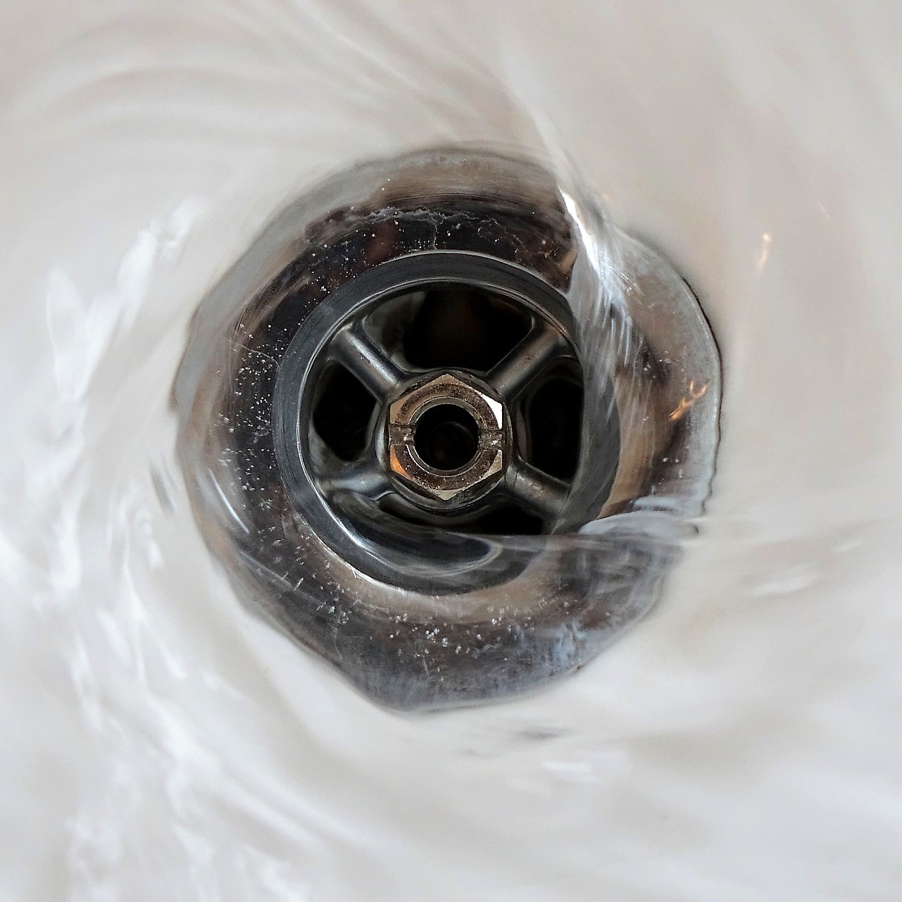 Photo of water flowing down a bathtub drain.