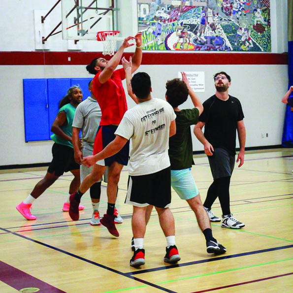 A group of adult men play basketball at the Georgie Duke Sports Center