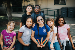 A group of students sitting next to a teacher.