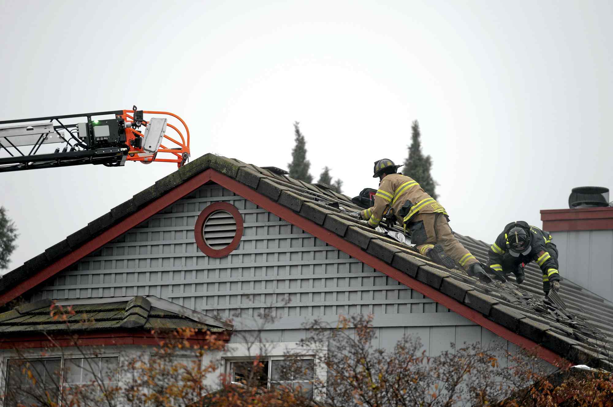 Two firefighters climbing on a house roof